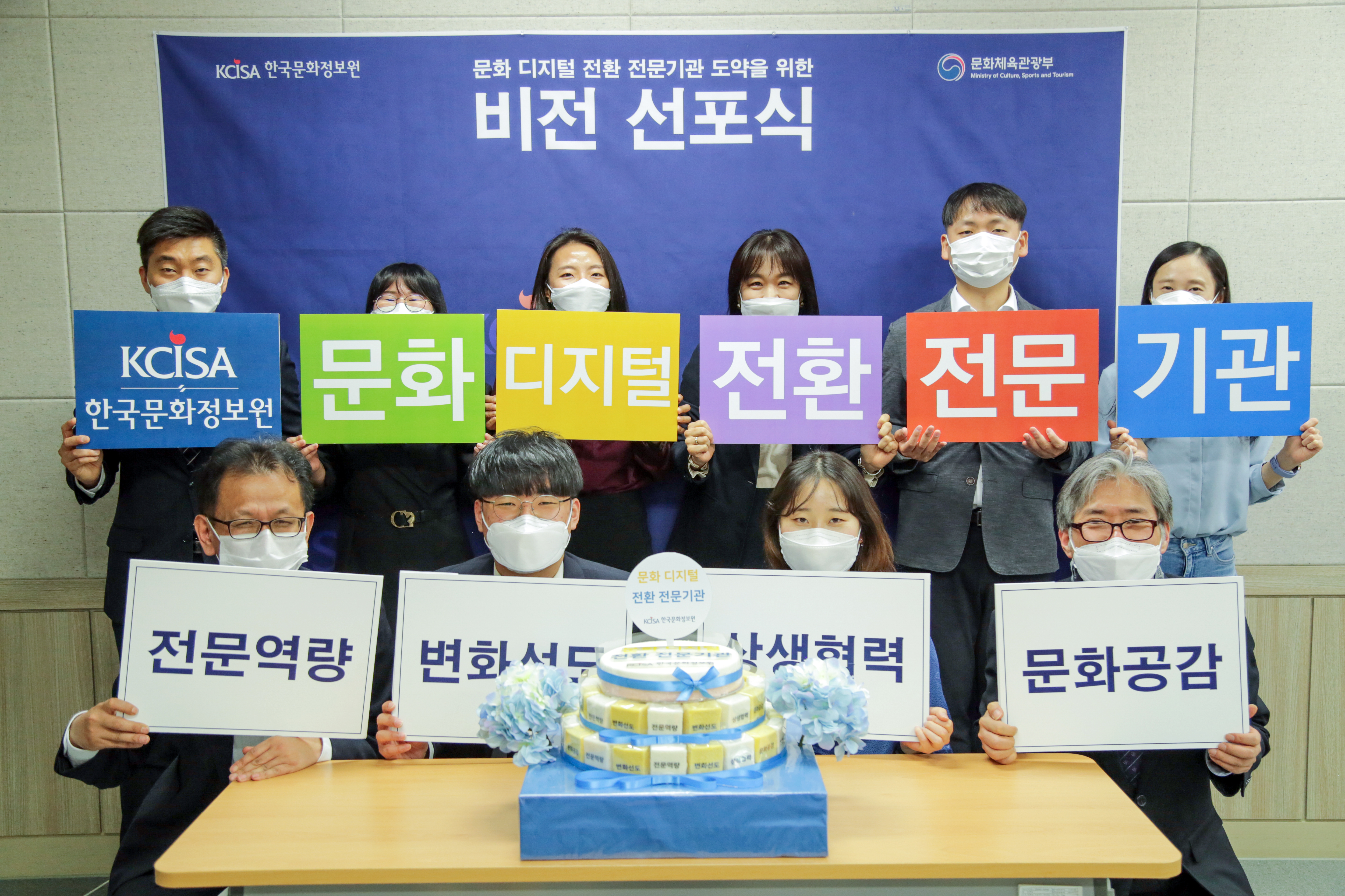 한국문화정보원 비전 선포식에 홍희경 원장과 임직원들이 비전과 핵심가치 문구 피켓을 들고 있는 사진이다. 